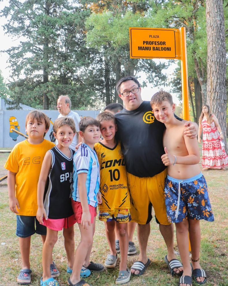 Los niños del Club Comunicaciones junto a Manu Baldoni y el cartel de la plaza de juegos infantiles que lleva su nombre.